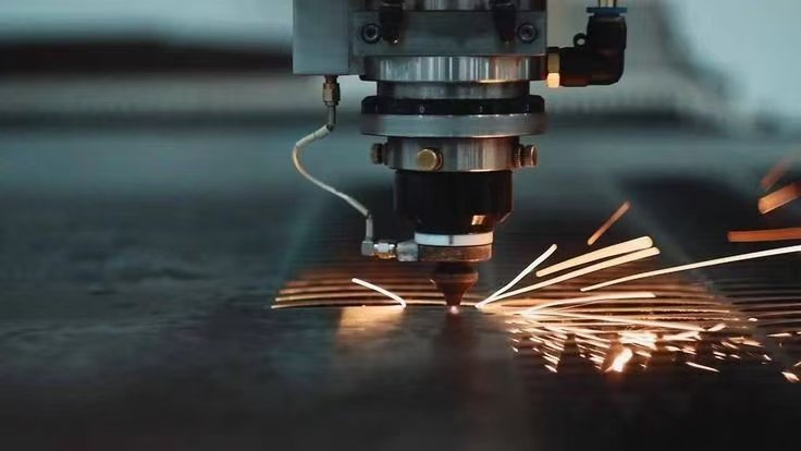 Fiber laser cutting head cutting metal with visible sparks